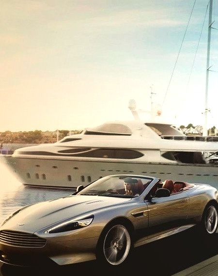 Aston Martin speeding by a Luxury Yacht